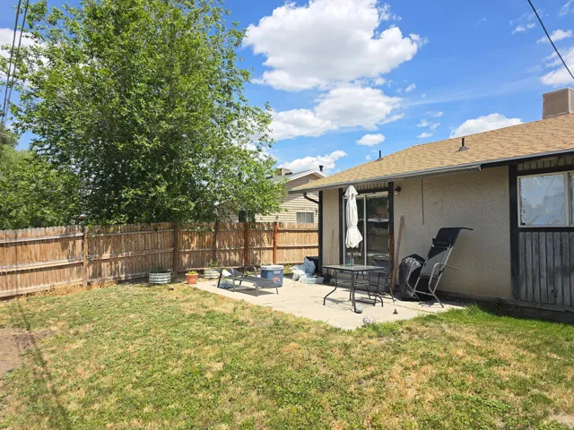 Expansive backyard featuring a concrete patio, sliding glass door access to the interior, and a wood privacy fence
