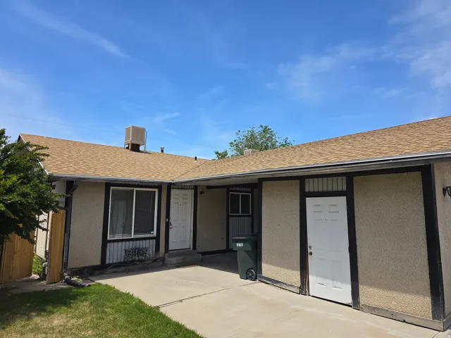 Exterior facade featuring a tan shingle roof, stucco siding, and dark trim details