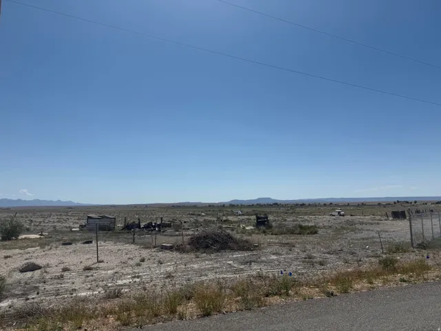 Expansive desert landscape featuring open ground, distant mountain ranges, and clear skies