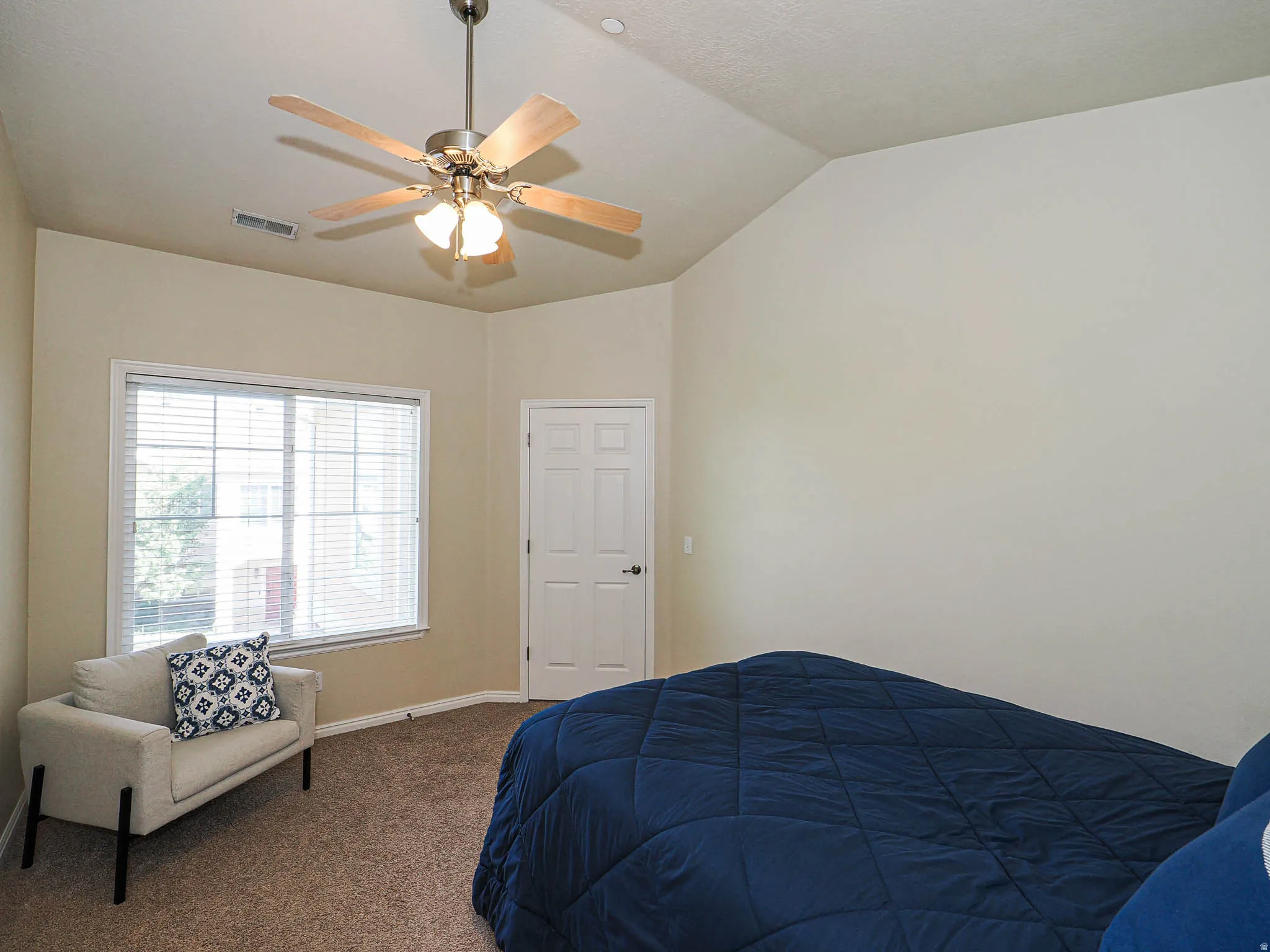 Bedroom featuring vaulted ceilings, a ceiling fan with light fixture, carpeted flooring, a two-panel door, and a window with blinds