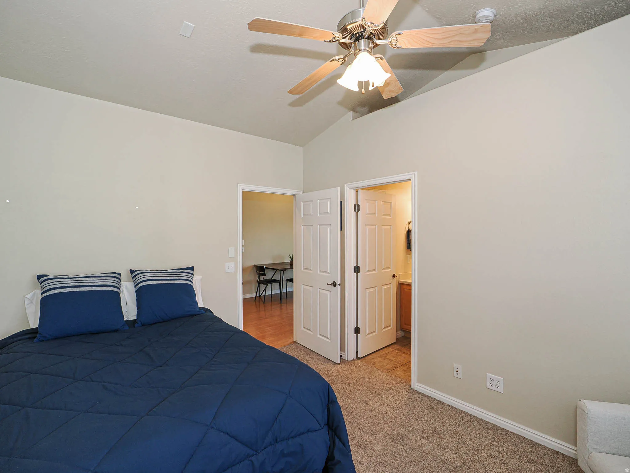 Bedroom featuring neutral wall paint, vaulted ceiling, and carpet flooring