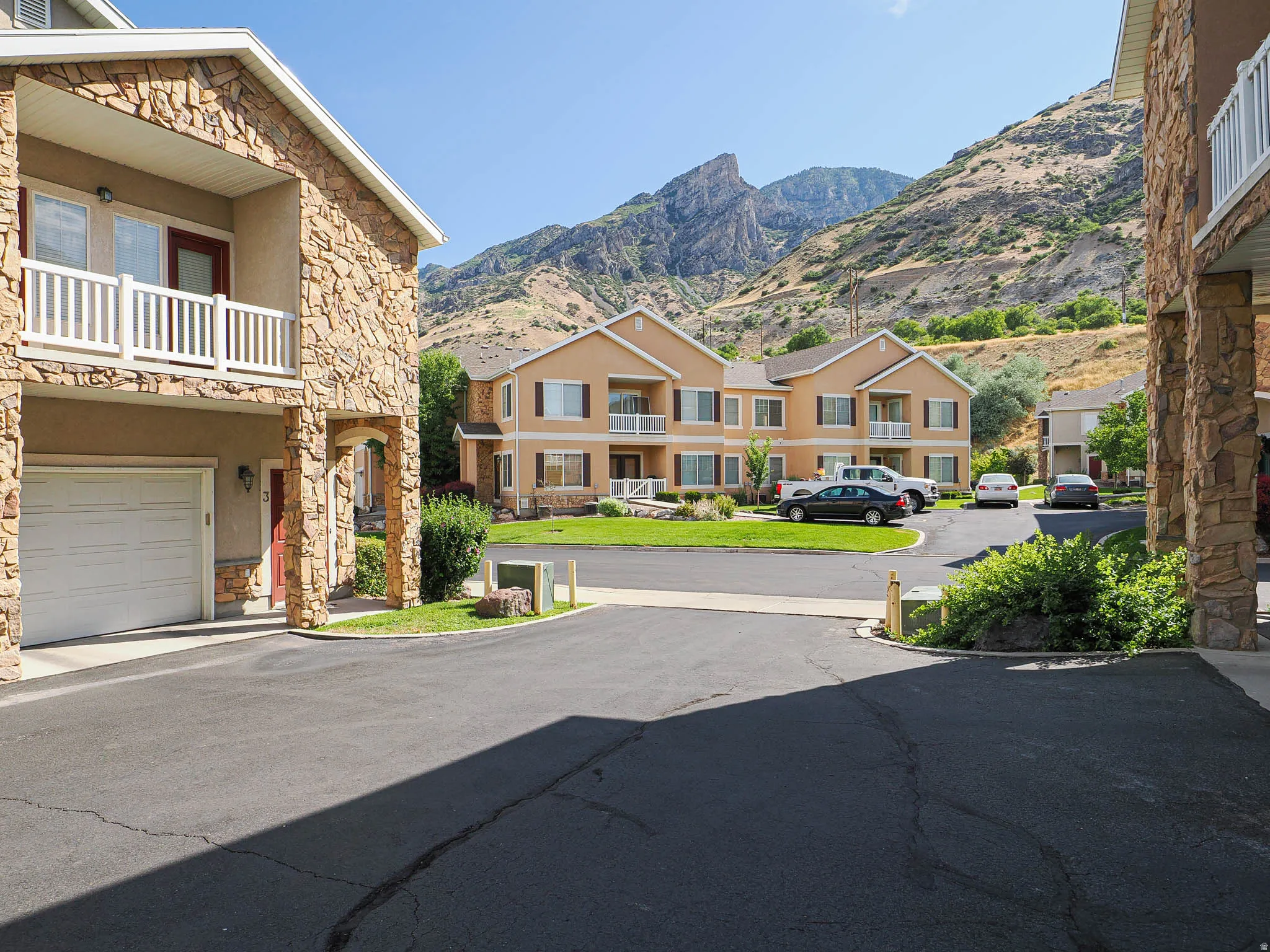 Residential building featuring stone veneer accents, an attached garage, and a private balcony with white railings