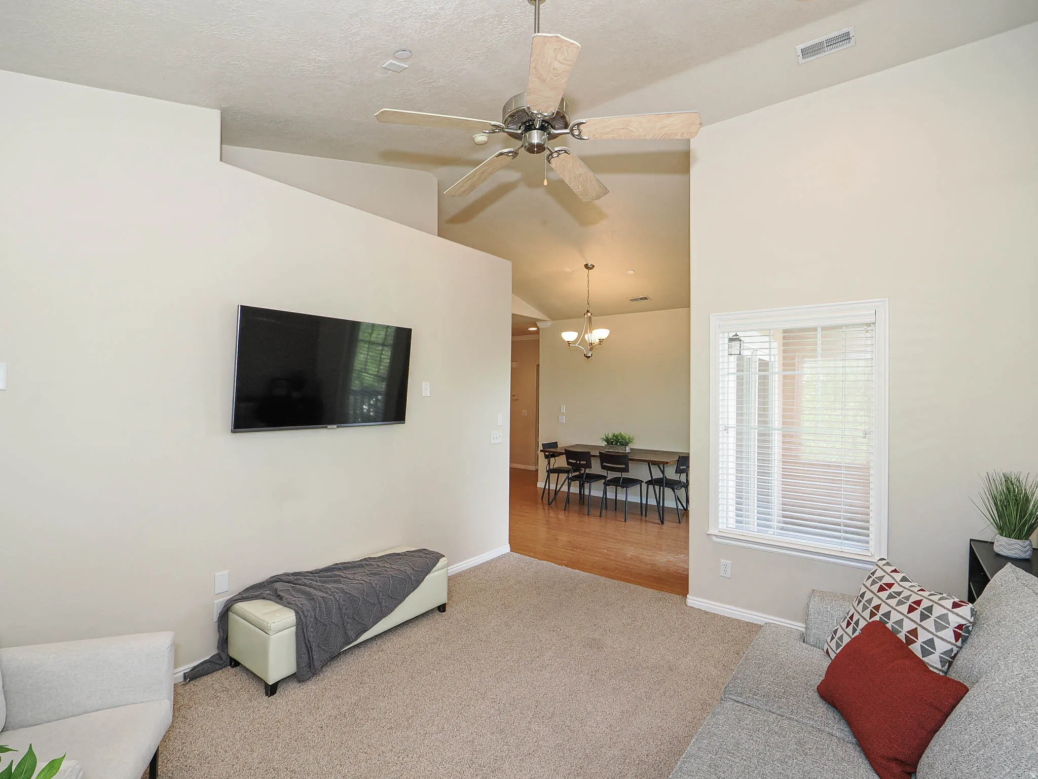 Vaulted ceiling with a ceiling fan, carpeted flooring, and a window with blinds