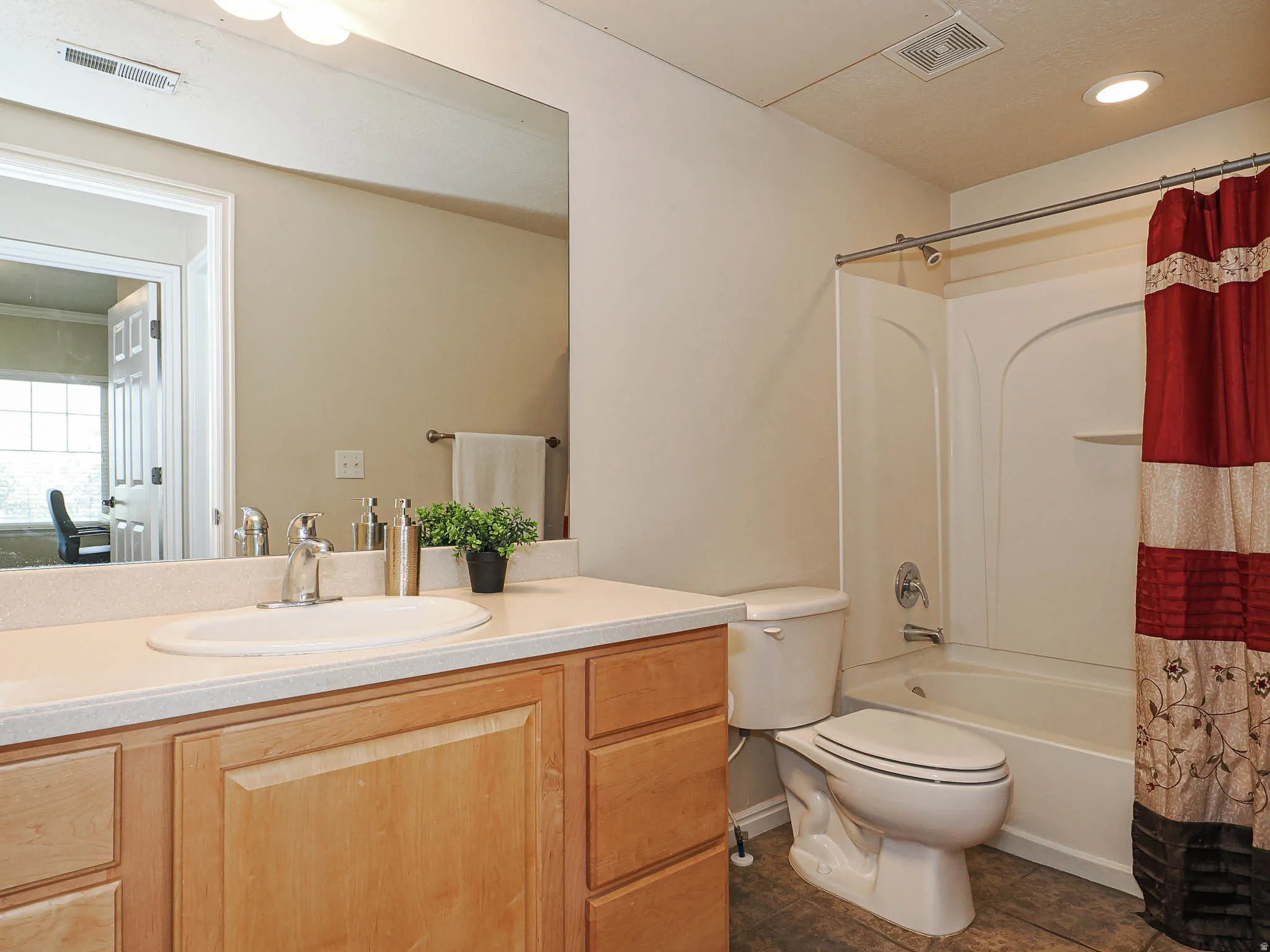 Bathroom featuring a light-toned wood vanity, integrated sink, and substantial mirror