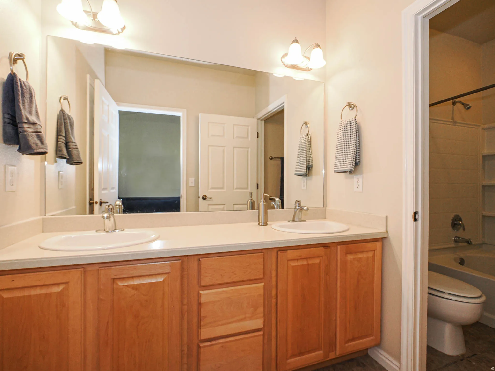 Double vanity with light wood cabinetry, white countertops, and dual undermount sinks