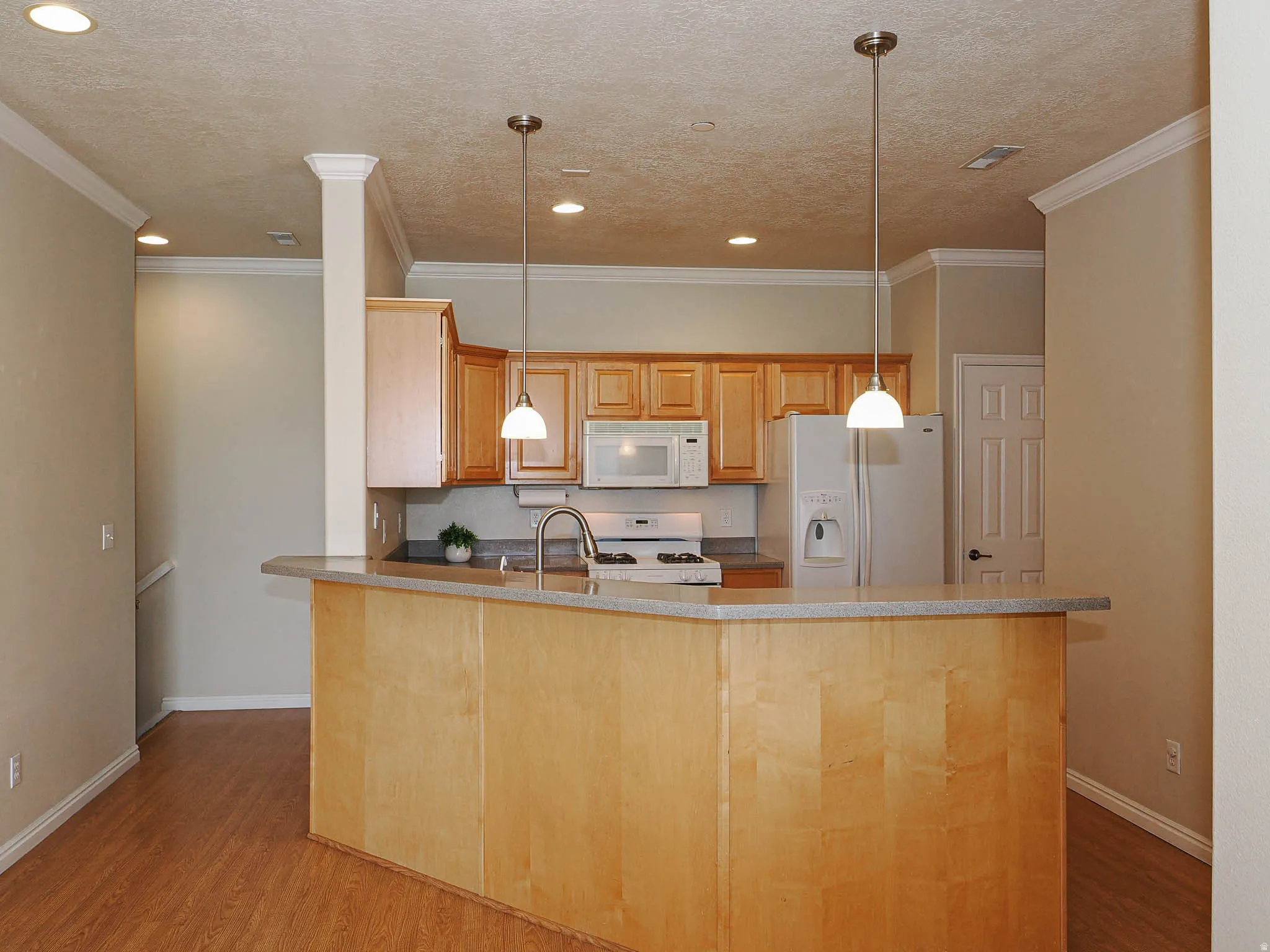 Kitchen featuring a peninsula island with counter seating, wood-finish flooring, recessed lighting, and crown molding