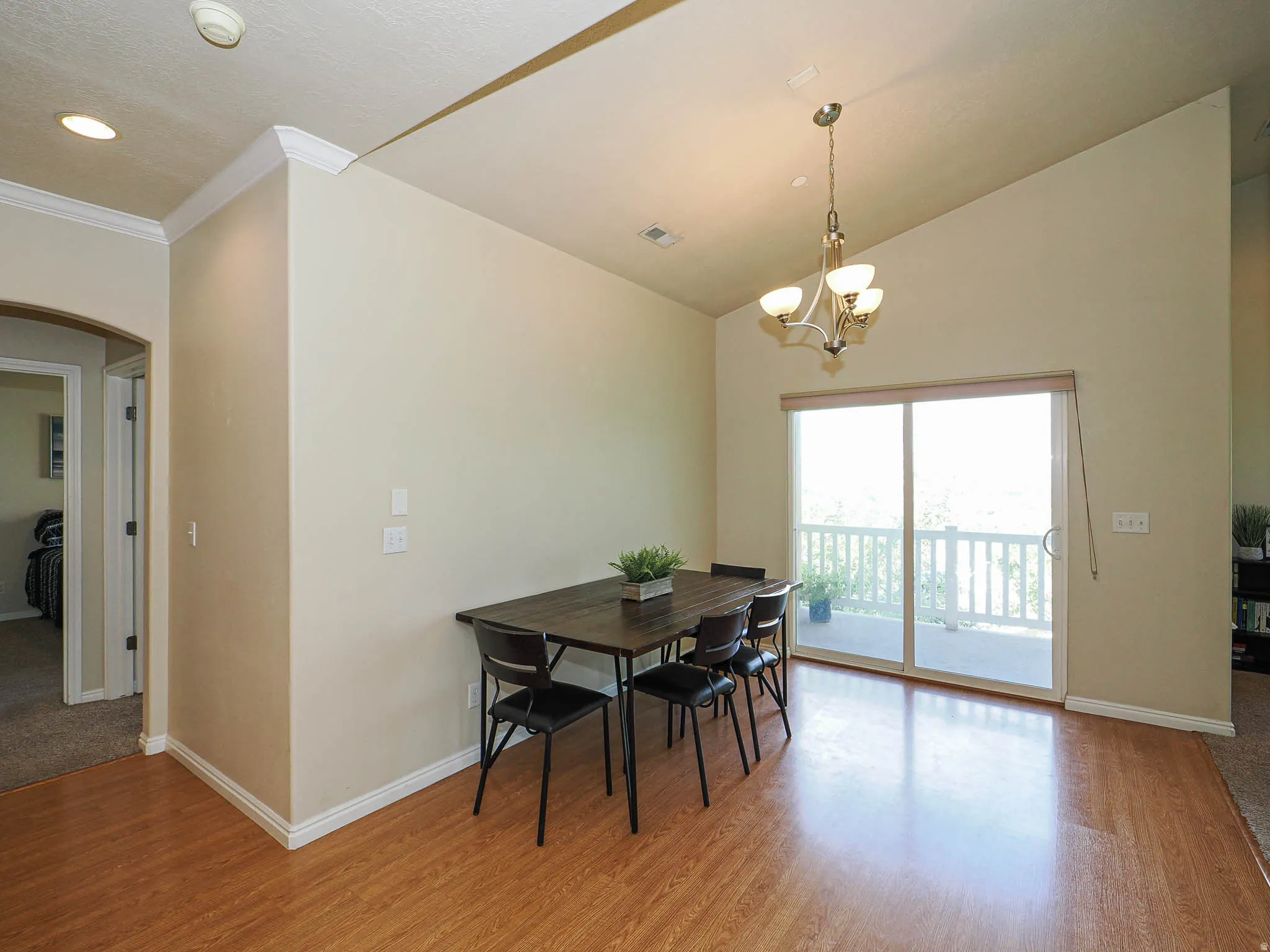 Dining area featuring wood-finish flooring, a vaulted ceiling, and sliding glass doors opening to an outdoor space with white railings