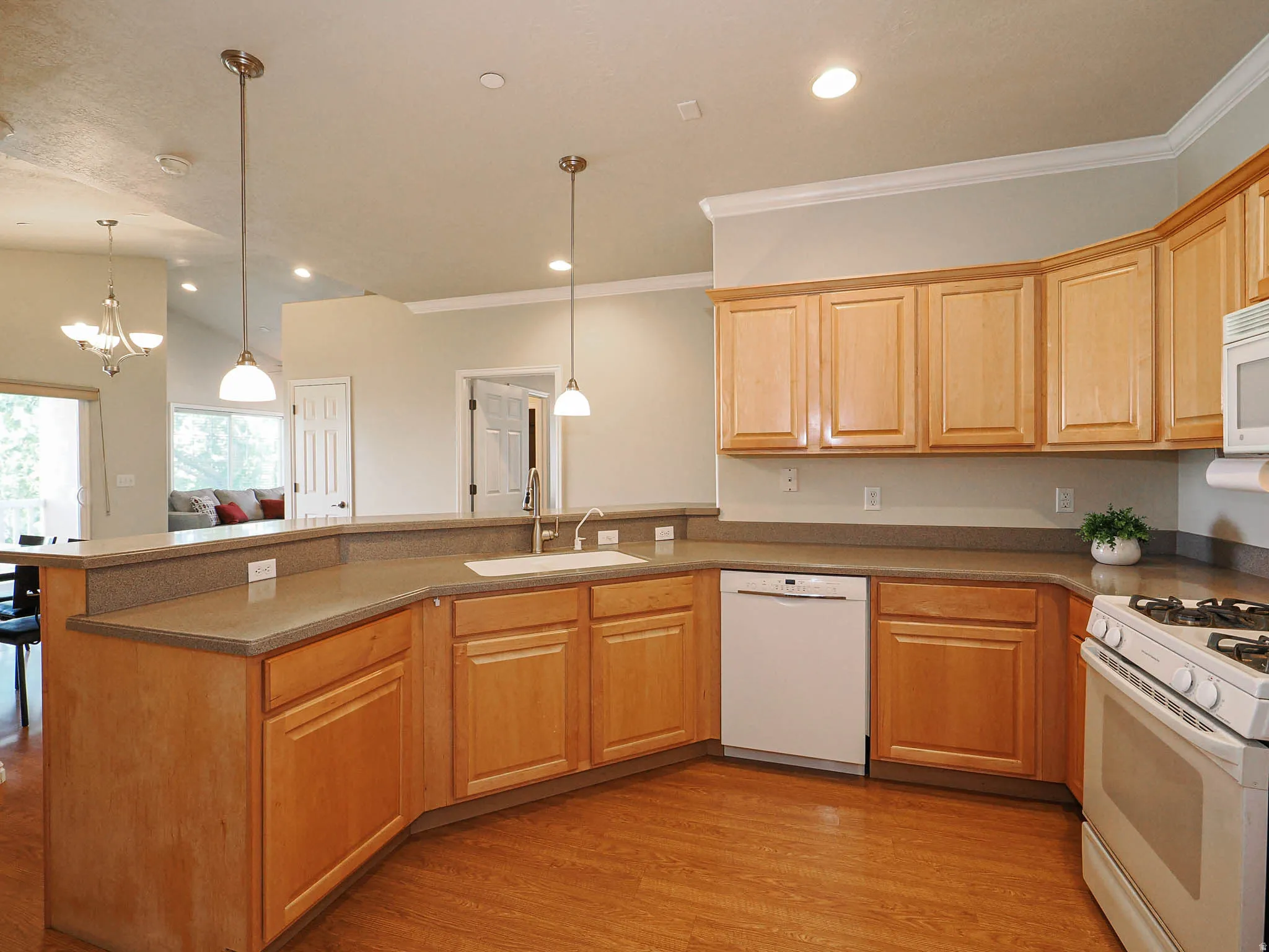 U-shaped kitchen featuring wood-finish flooring, light wood cabinetry, stone-finish countertops, and a full suite of appliances