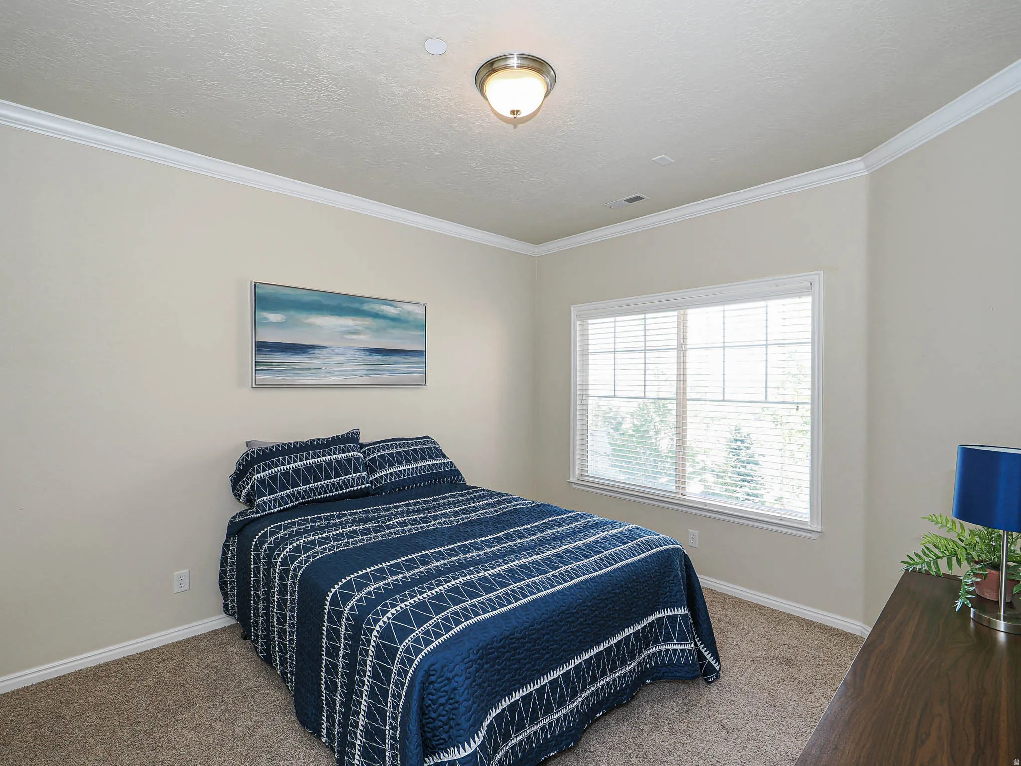 Spacious room featuring neutral-toned walls, crown molding, and plush carpeting