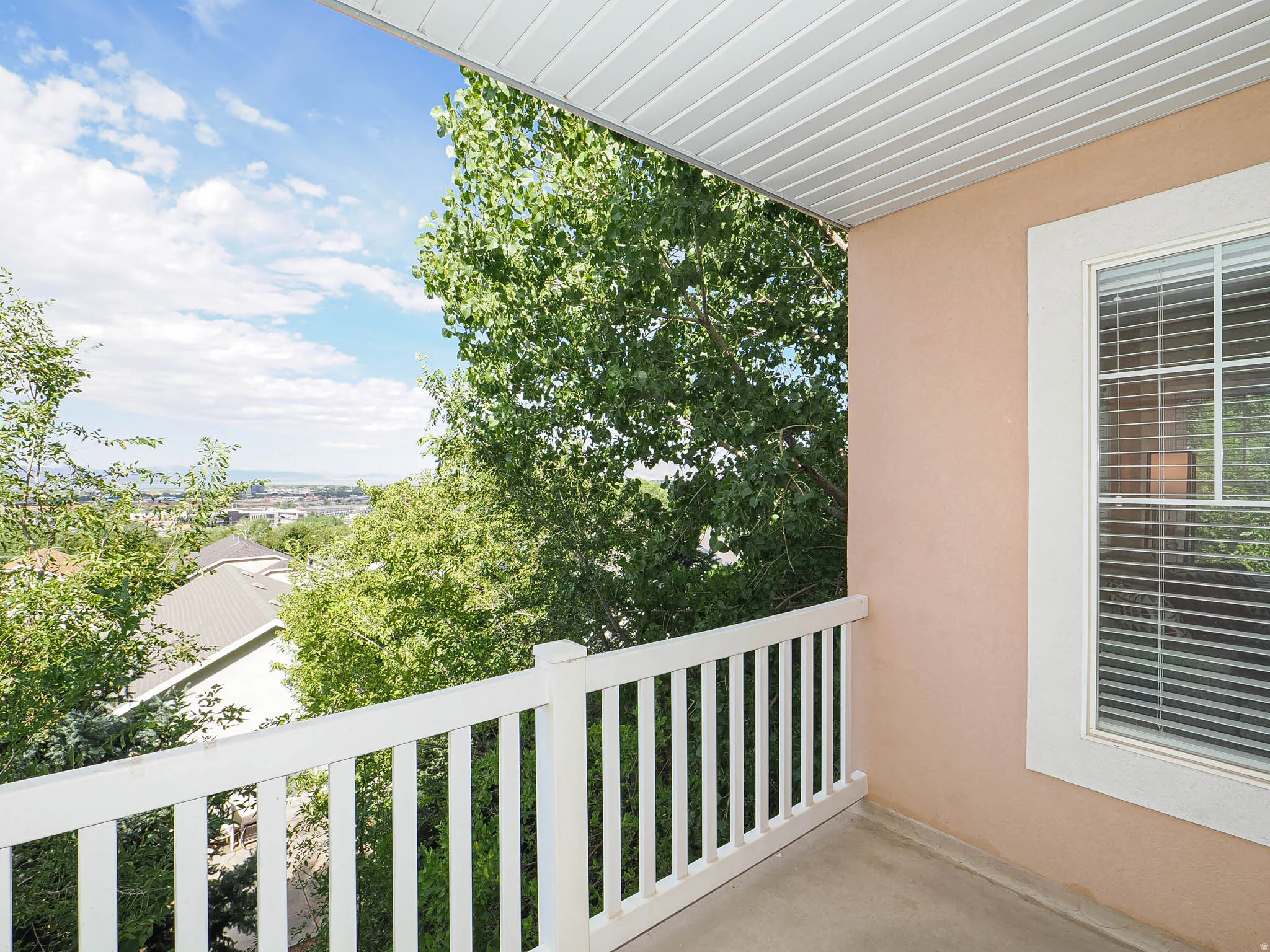 Upper-level outdoor balcony with a white railing and textured stucco exterior