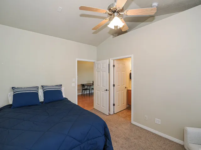 Bedroom featuring neutral wall paint, vaulted ceiling, and carpet flooring