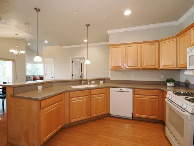 U-shaped kitchen featuring wood-finish flooring, light wood cabinetry, stone-finish countertops, and a full suite of appliances