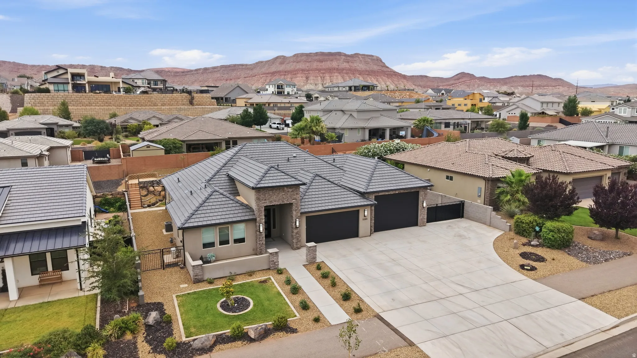 Contemporary stucco and stone exterior featuring a tiled roof, paver driveway, and an integrated two-car garage