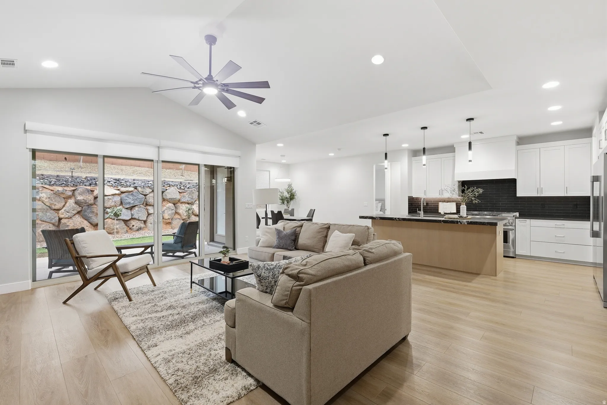 Open-concept living area featuring vaulted ceilings, wood-finish flooring, and recessed lighting