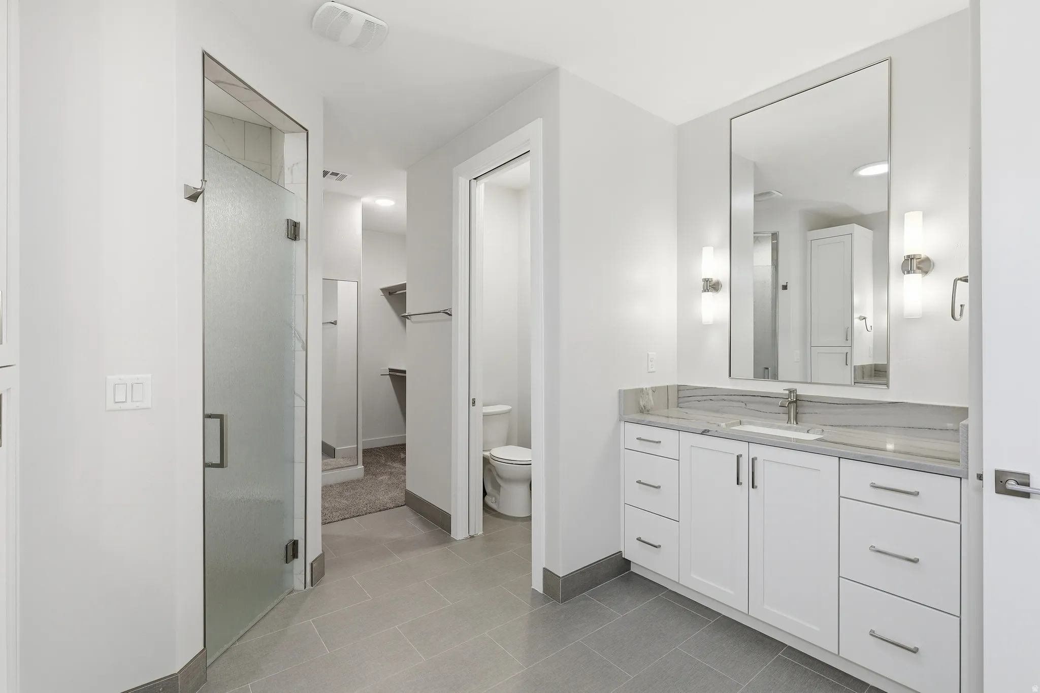 Contemporary bathroom featuring a single vanity with stone countertop, undermount sink, and brushed nickel hardware