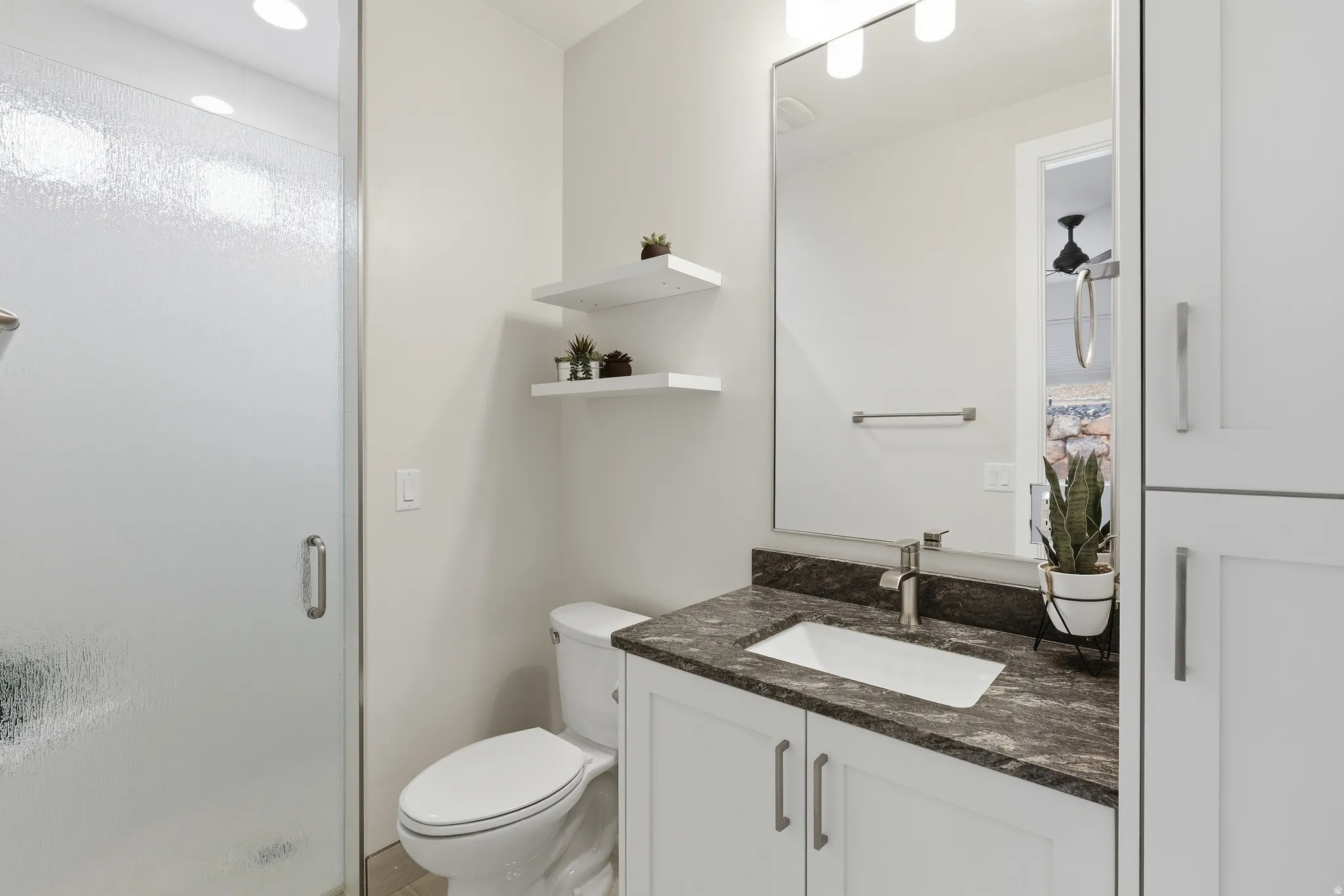 Bathroom vanity featuring a dark granite countertop, undermount sink, and brushed nickel faucet