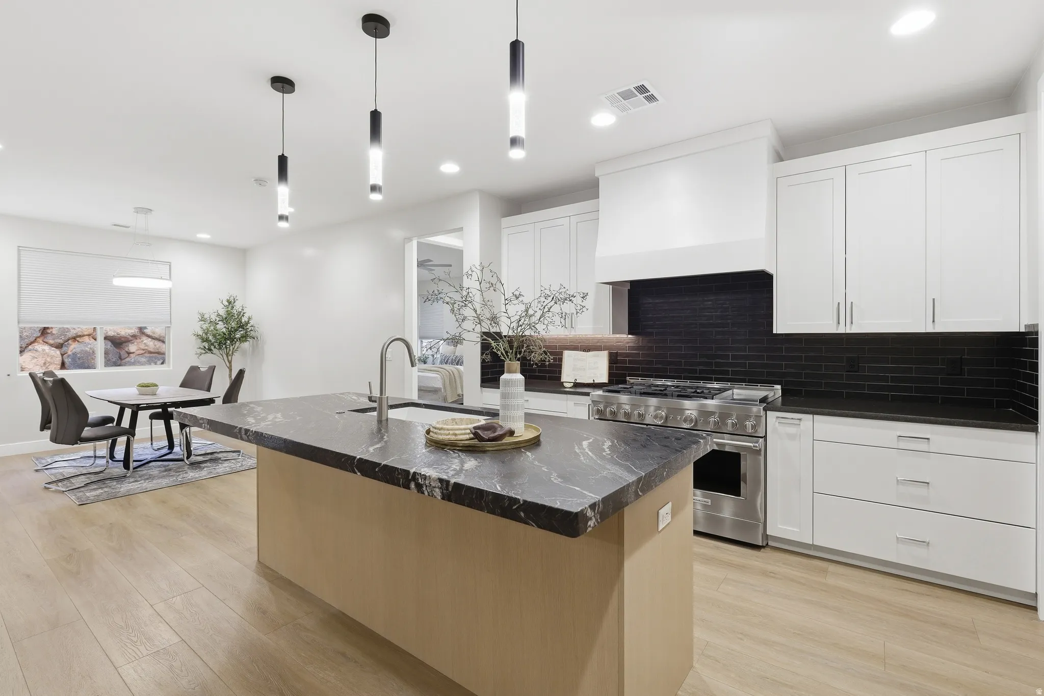 Kitchen featuring a large island with a dark stone countertop, undermount sink, and contemporary pendant lighting