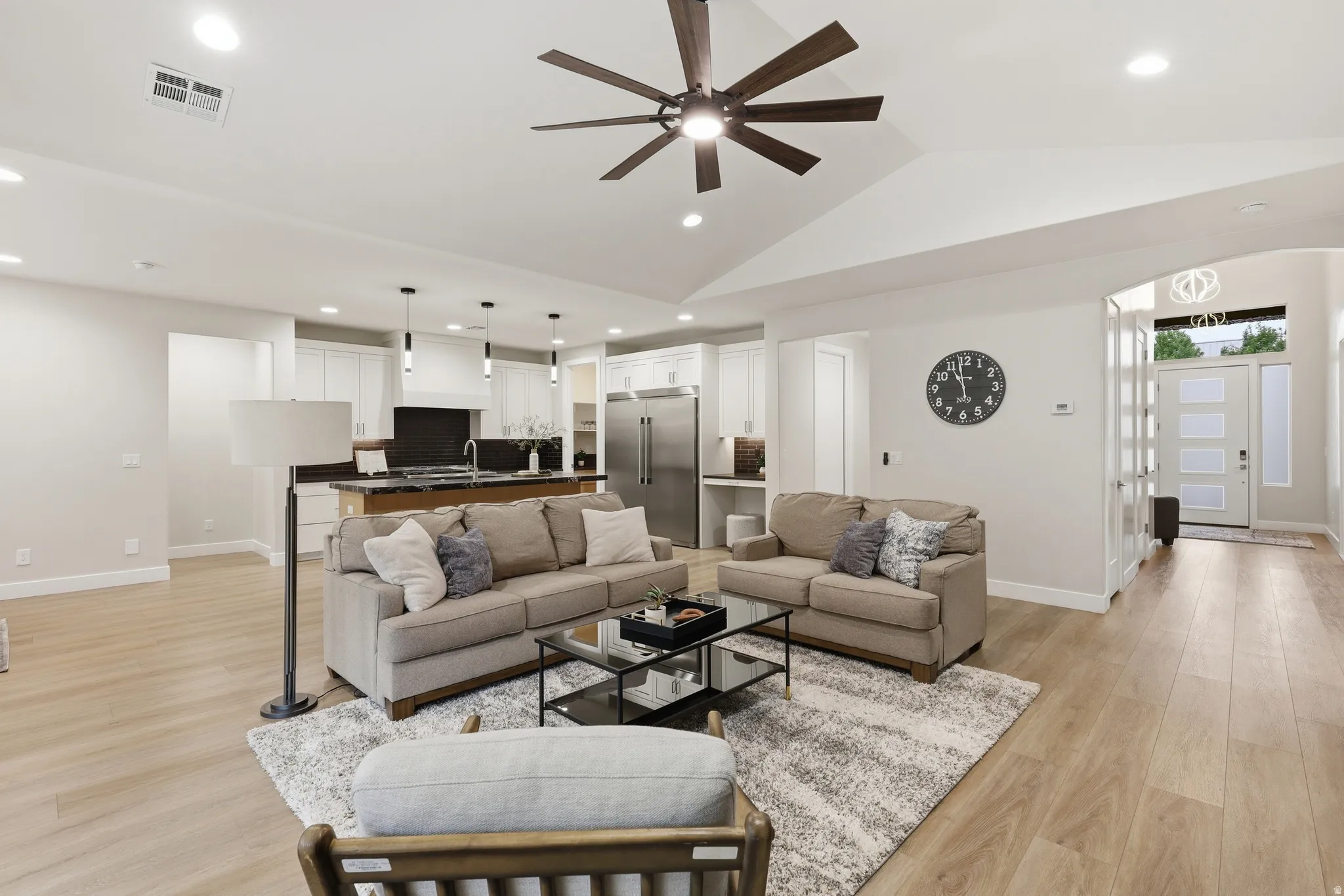 Open-concept living space featuring wood-finish flooring, recessed lighting, and a vaulted ceiling with a ceiling fan