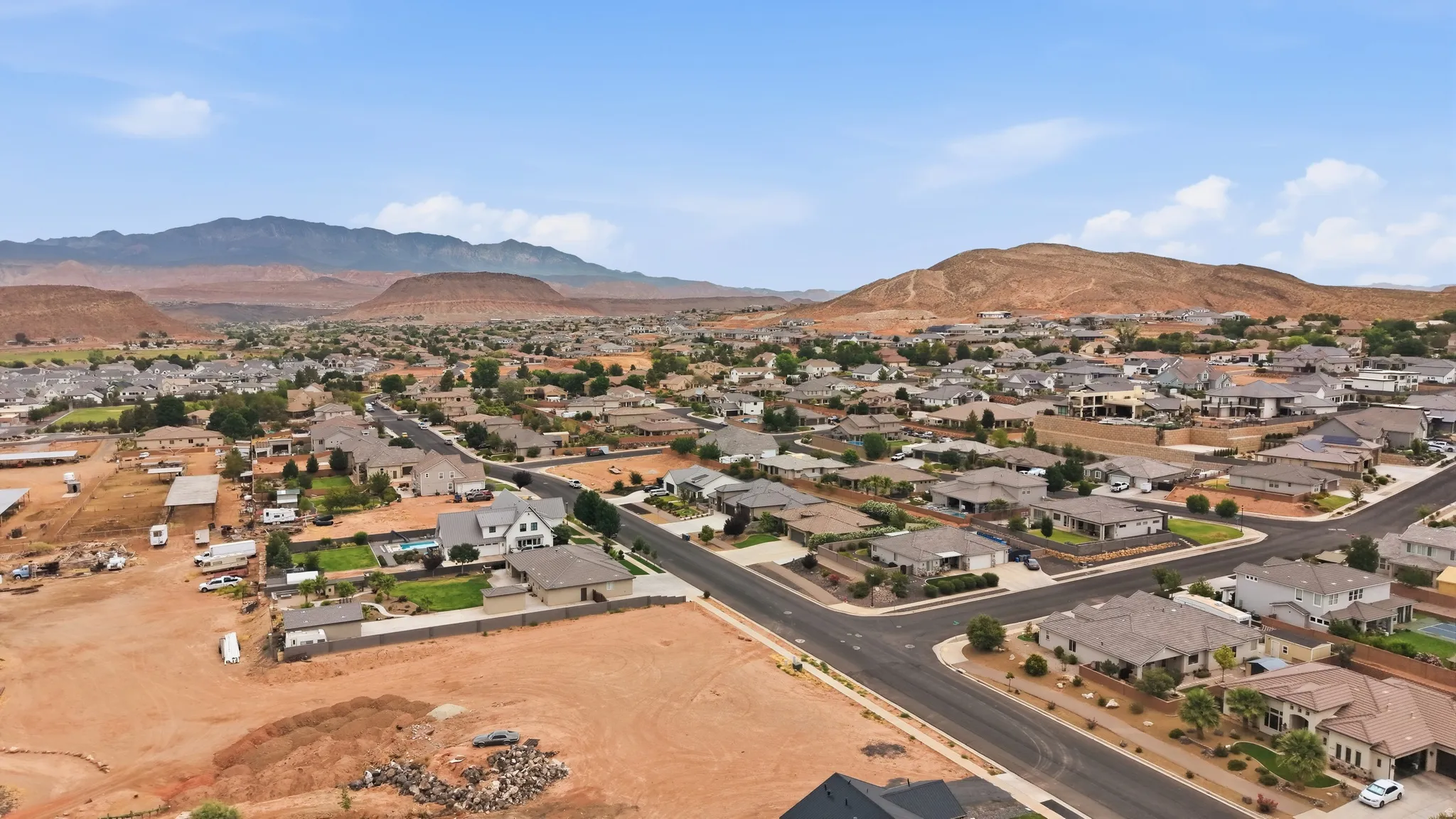 Expansive residential area with a prominent red rock mountain backdrop, featuring a mix of established homes and undeveloped land