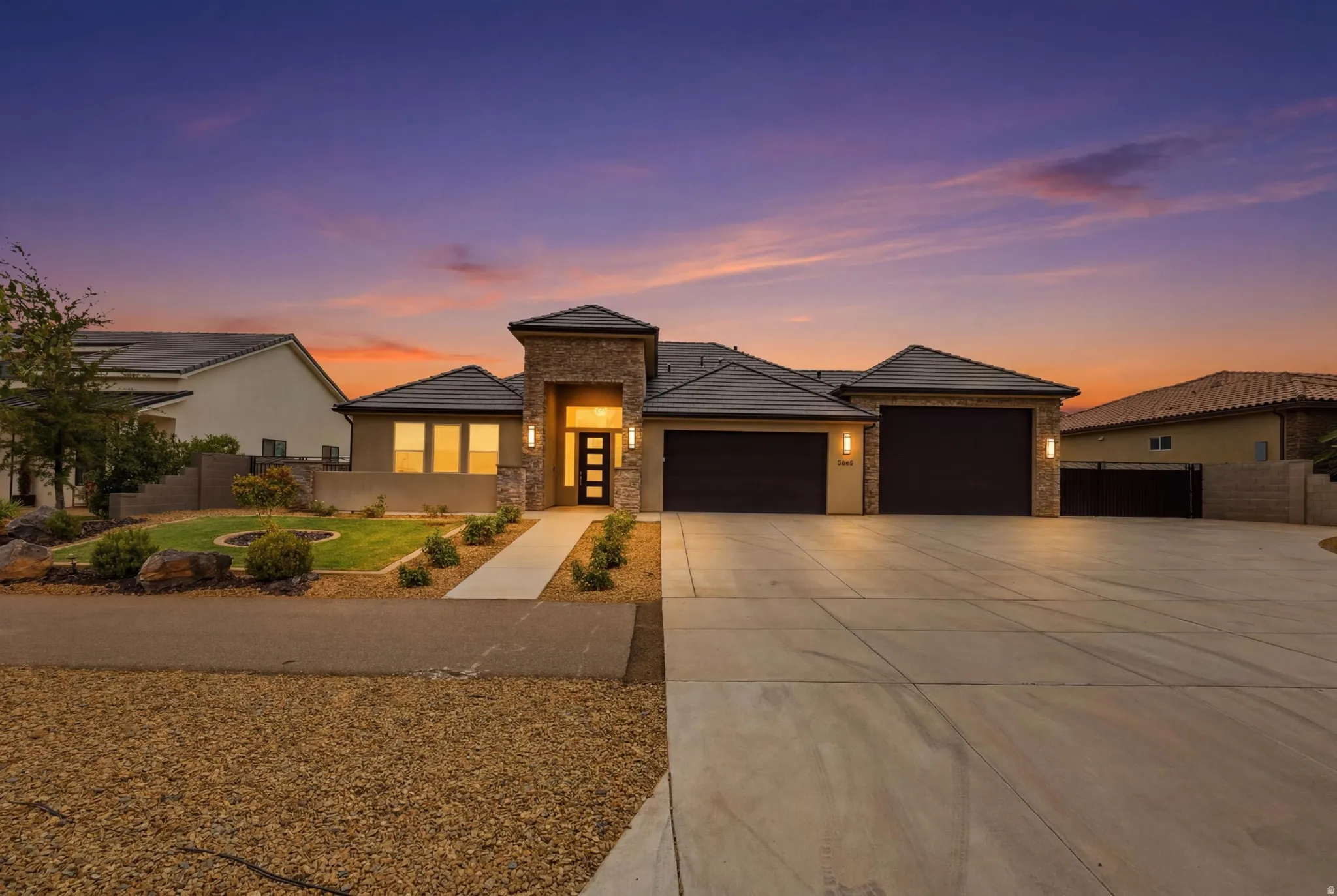 Contemporary stucco exterior featuring stone accents, a multi-car concrete driveway, and a welcoming entryway with an opaque paneled door