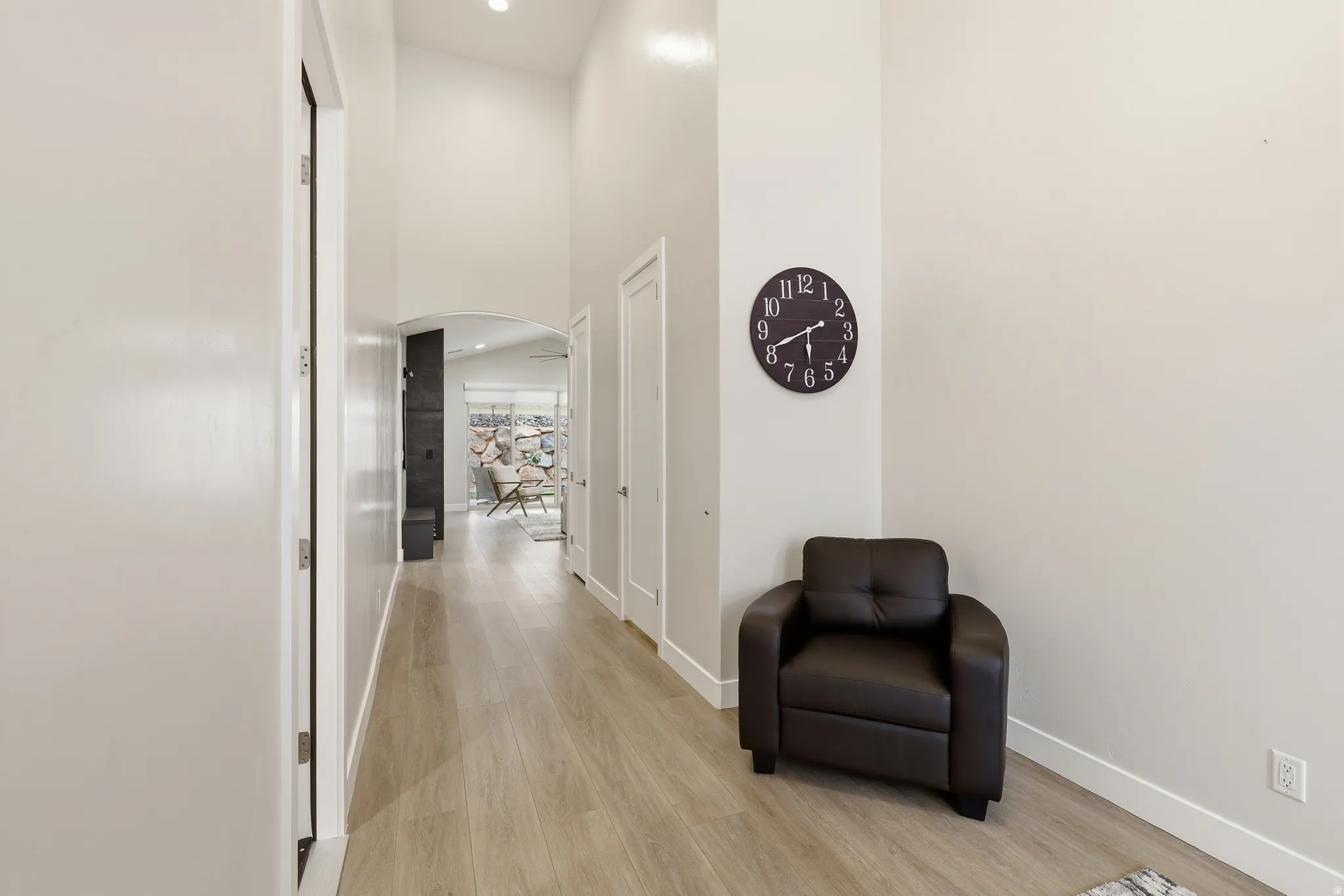 Hallway featuring wood-finish flooring, vaulted ceiling, and an arched doorway