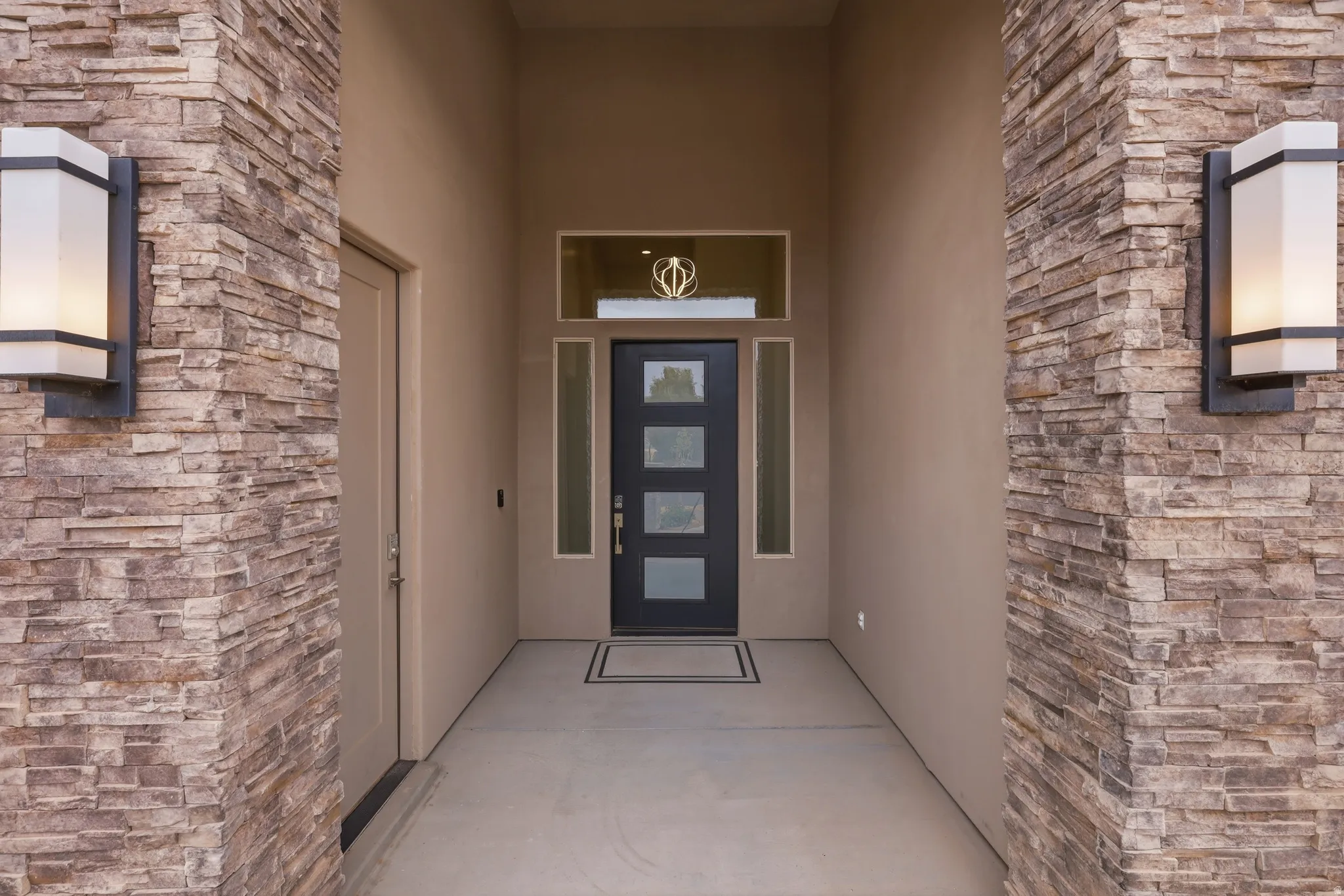 Stone veneer columns framing a recessed entry with sconce lighting