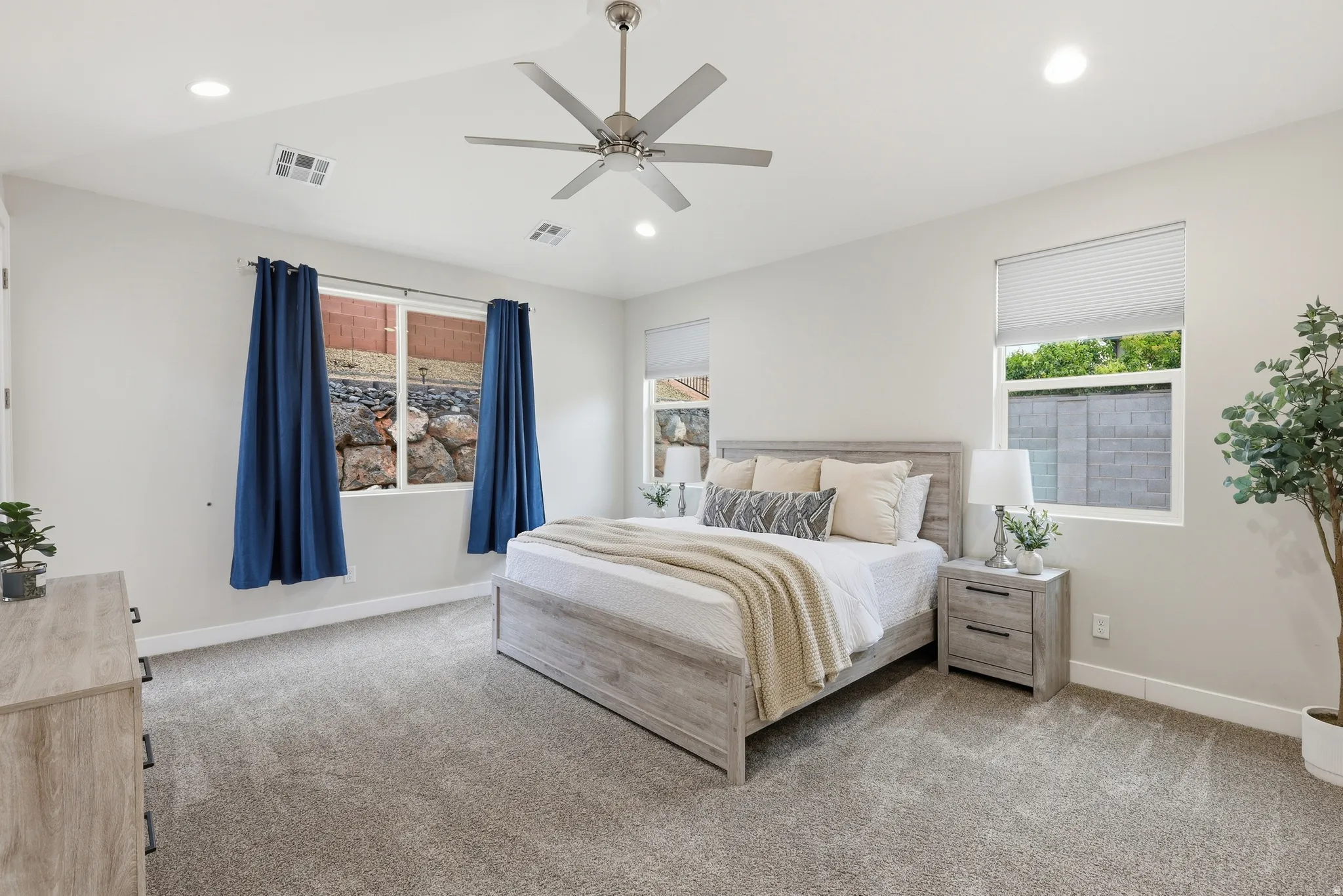 Spacious room featuring light gray carpeting, recessed lighting, white walls, and multiple windows