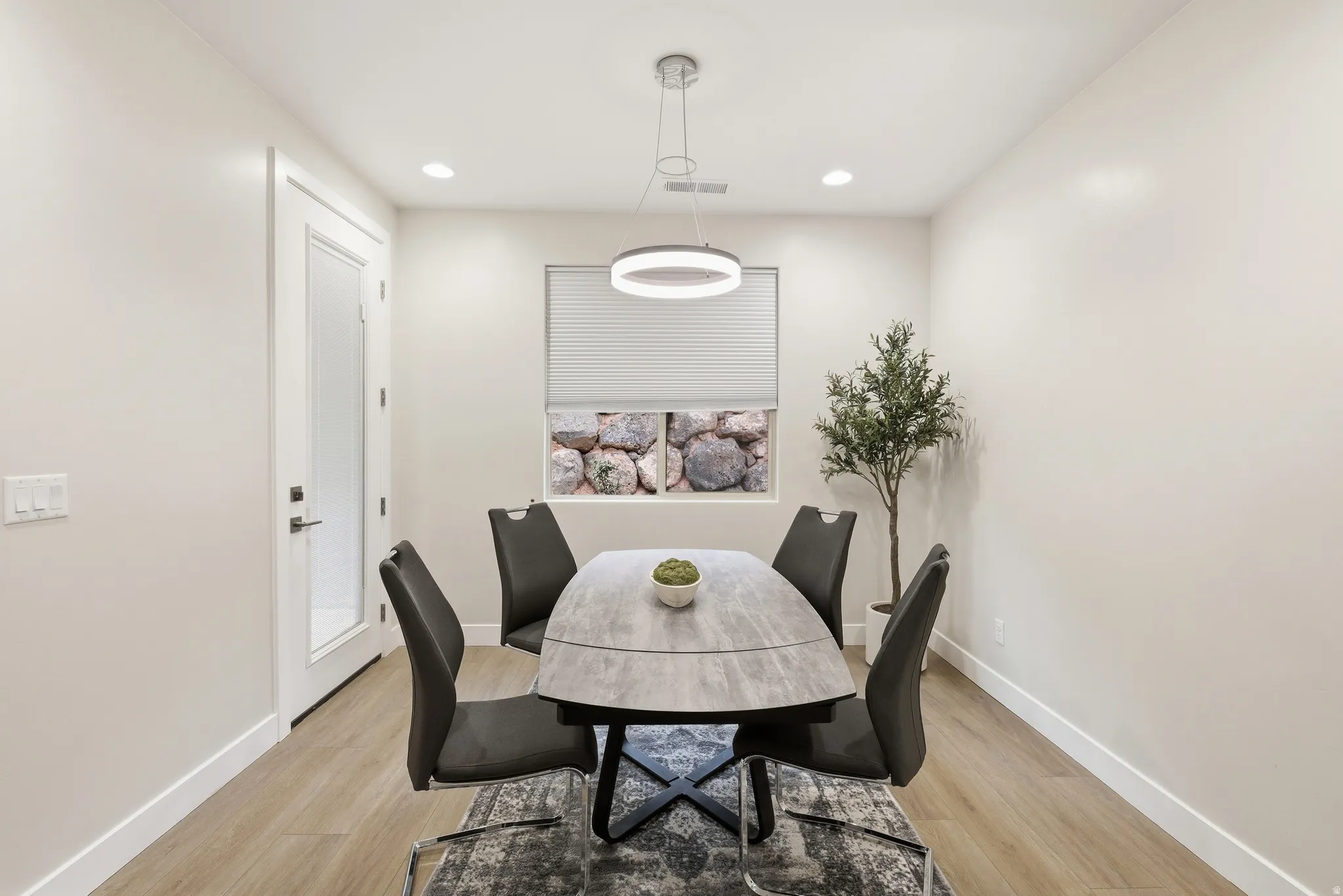 Light-filled dining area featuring wood-finish flooring, recessed lighting, and a modern circular chandelier