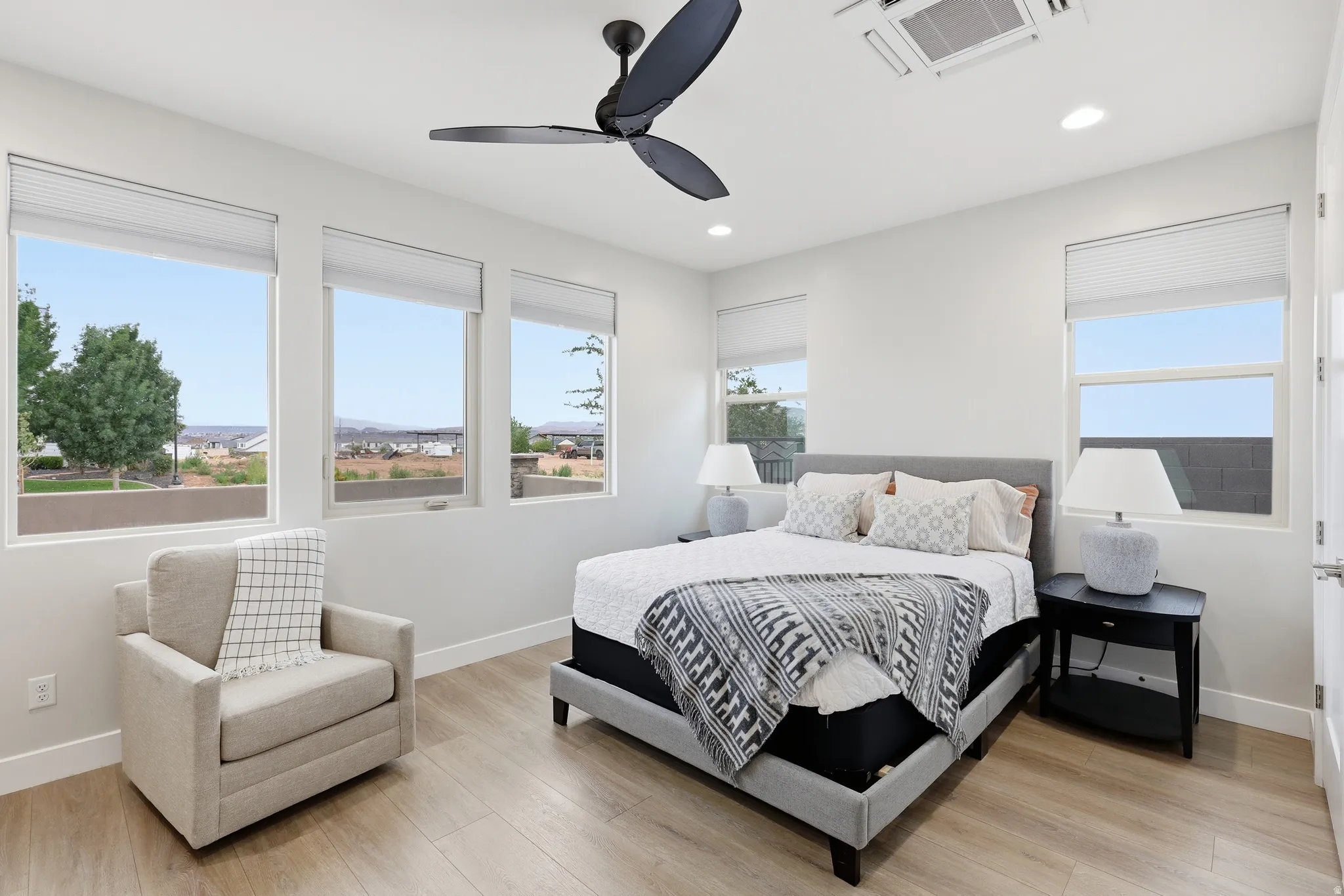 Spacious room featuring multiple windows with blinds, wood-finish flooring, a modern ceiling fan, and recessed lighting
