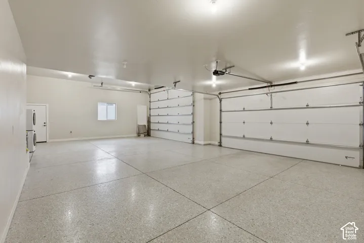 Spacious garage featuring a light-toned epoxy floor, multiple overhead lights, and two large garage doors with automatic openers