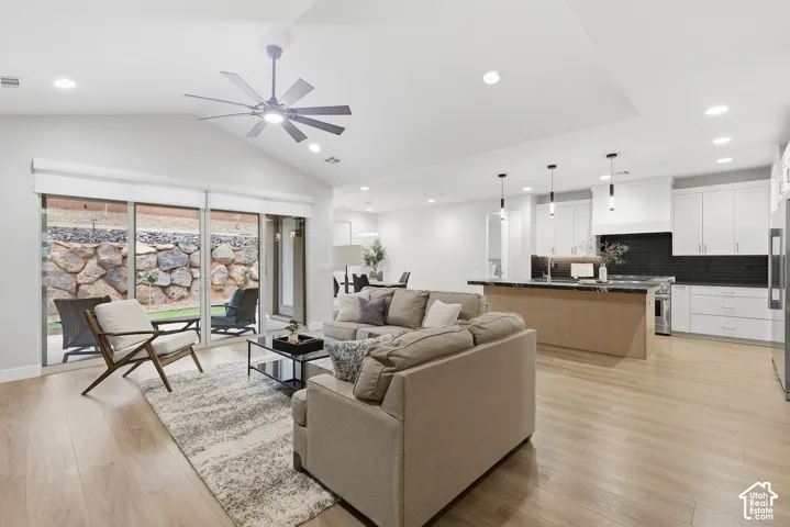 Open-concept living area featuring vaulted ceilings, wood-finish flooring, and recessed lighting