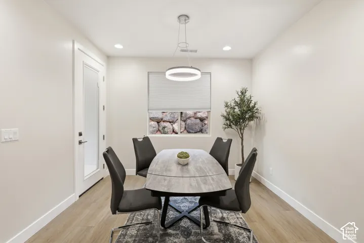 Light-filled dining area featuring wood-finish flooring, recessed lighting, and a modern circular chandelier