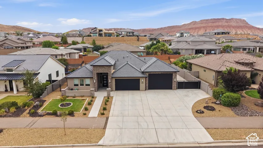 Contemporary residence featuring a grey tile roof, a multi-car driveway, and integrated garage doors