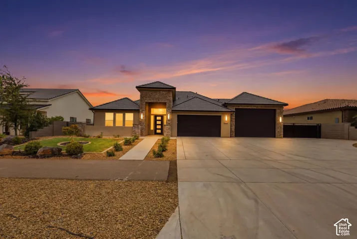 Contemporary stucco exterior featuring stone accents, a multi-car concrete driveway, and a welcoming entryway with an opaque paneled door