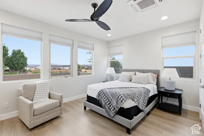 Spacious room featuring multiple windows with blinds, wood-finish flooring, a modern ceiling fan, and recessed lighting