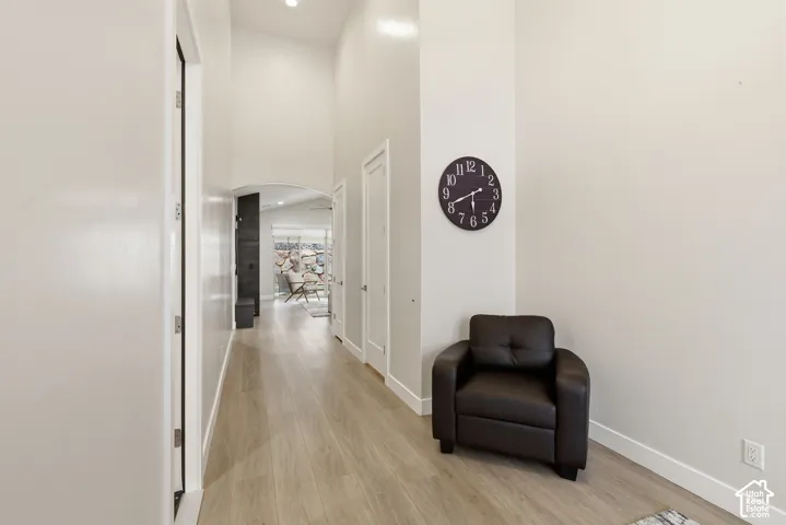 Hallway featuring wood-finish flooring, vaulted ceiling, and an arched doorway