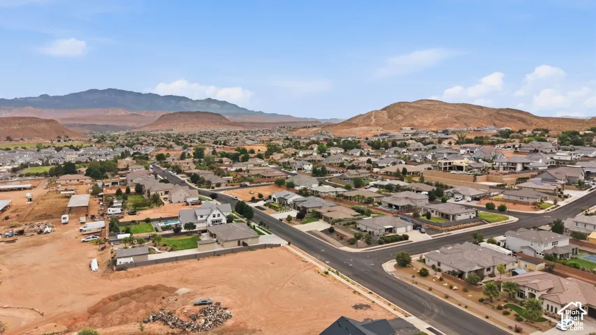 Expansive residential area with a prominent red rock mountain backdrop, featuring a mix of established homes and undeveloped land