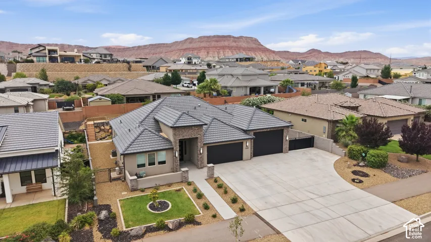 Contemporary stucco and stone exterior featuring a tiled roof, paver driveway, and an integrated two-car garage