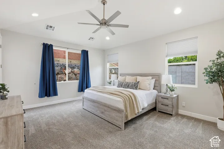 Spacious room featuring light gray carpeting, recessed lighting, white walls, and multiple windows