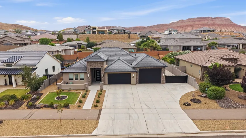 Contemporary residence featuring a grey tile roof, a multi-car driveway, and integrated garage doors