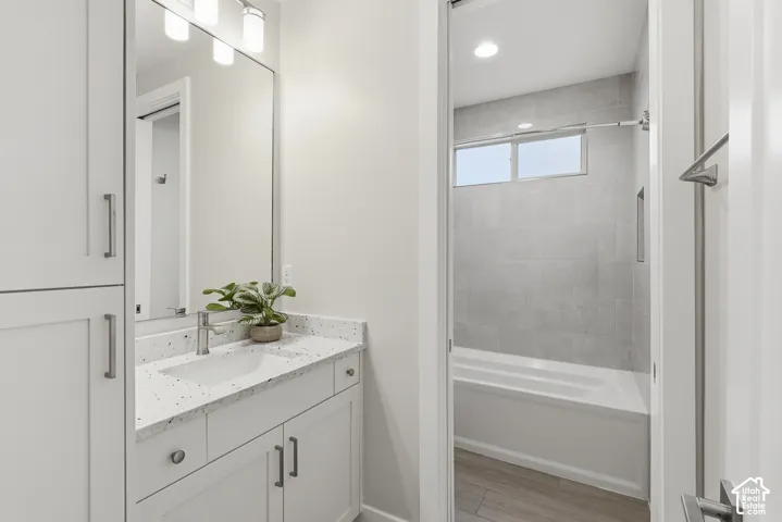 Bathroom featuring a vanity with a white countertop and integrated sink, brushed nickel faucet, and a large mirror