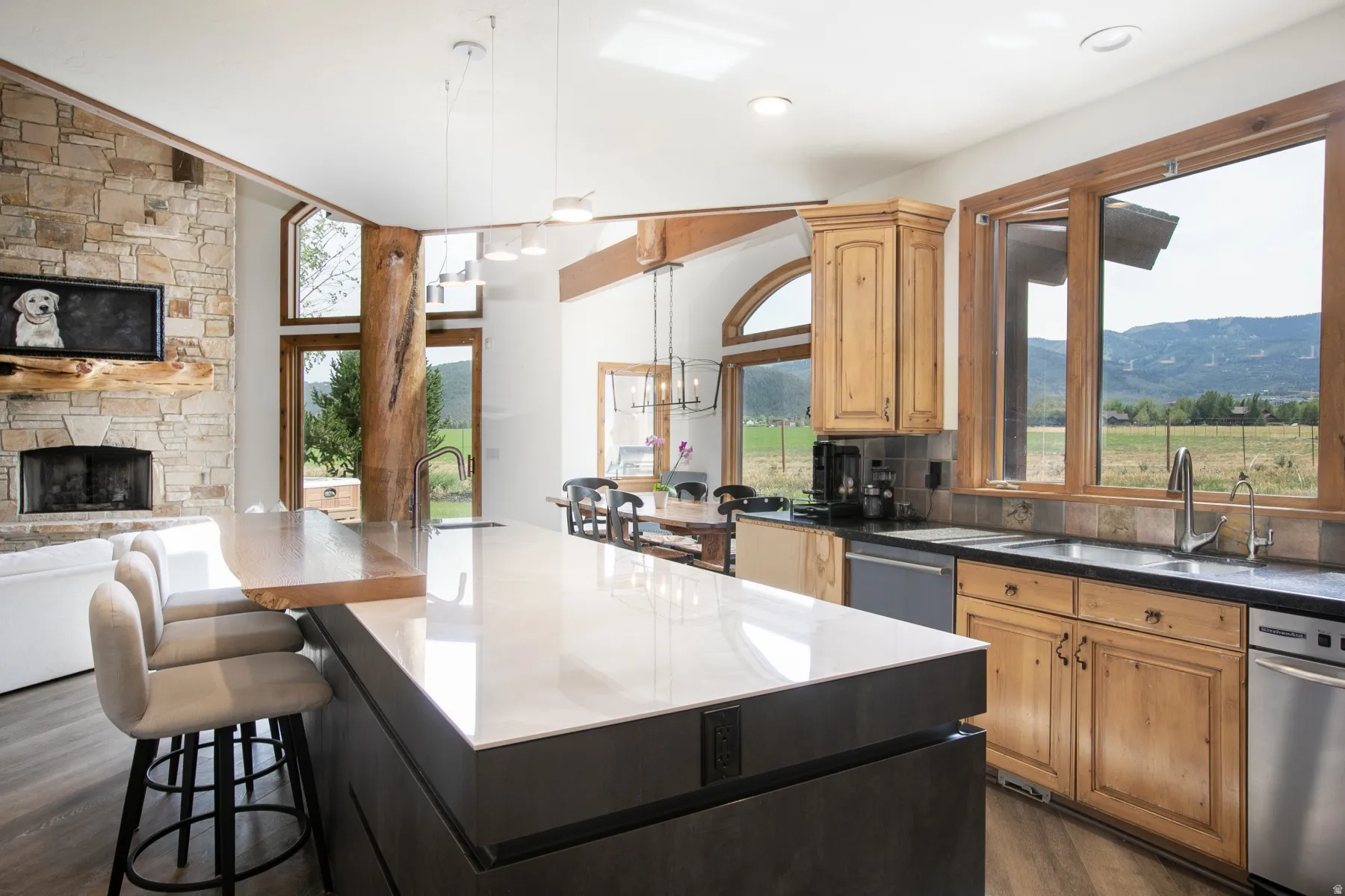 Spacious kitchen featuring a large island with a light-toned countertop, natural wood cabinetry, and stainless steel appliances