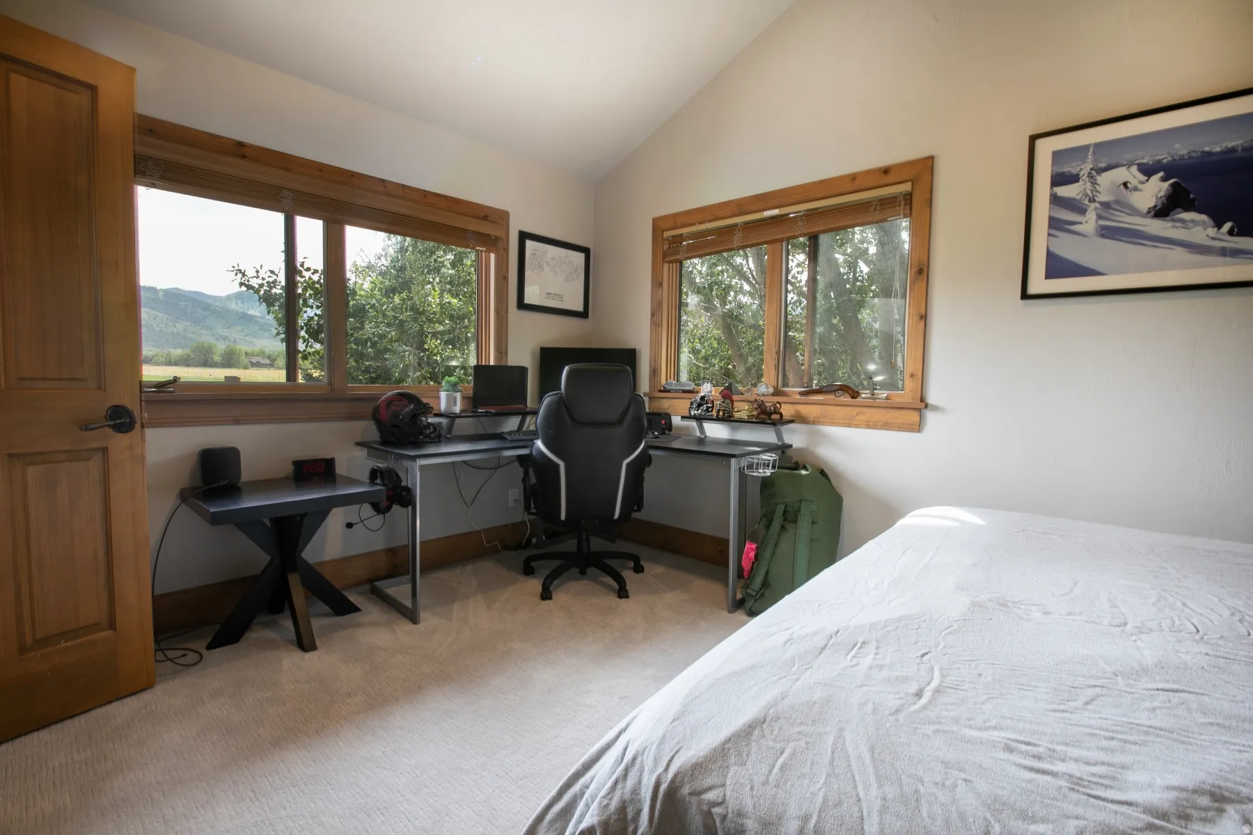 Room featuring two large windows, wood-finish trim, a vaulted ceiling, and light-toned carpet