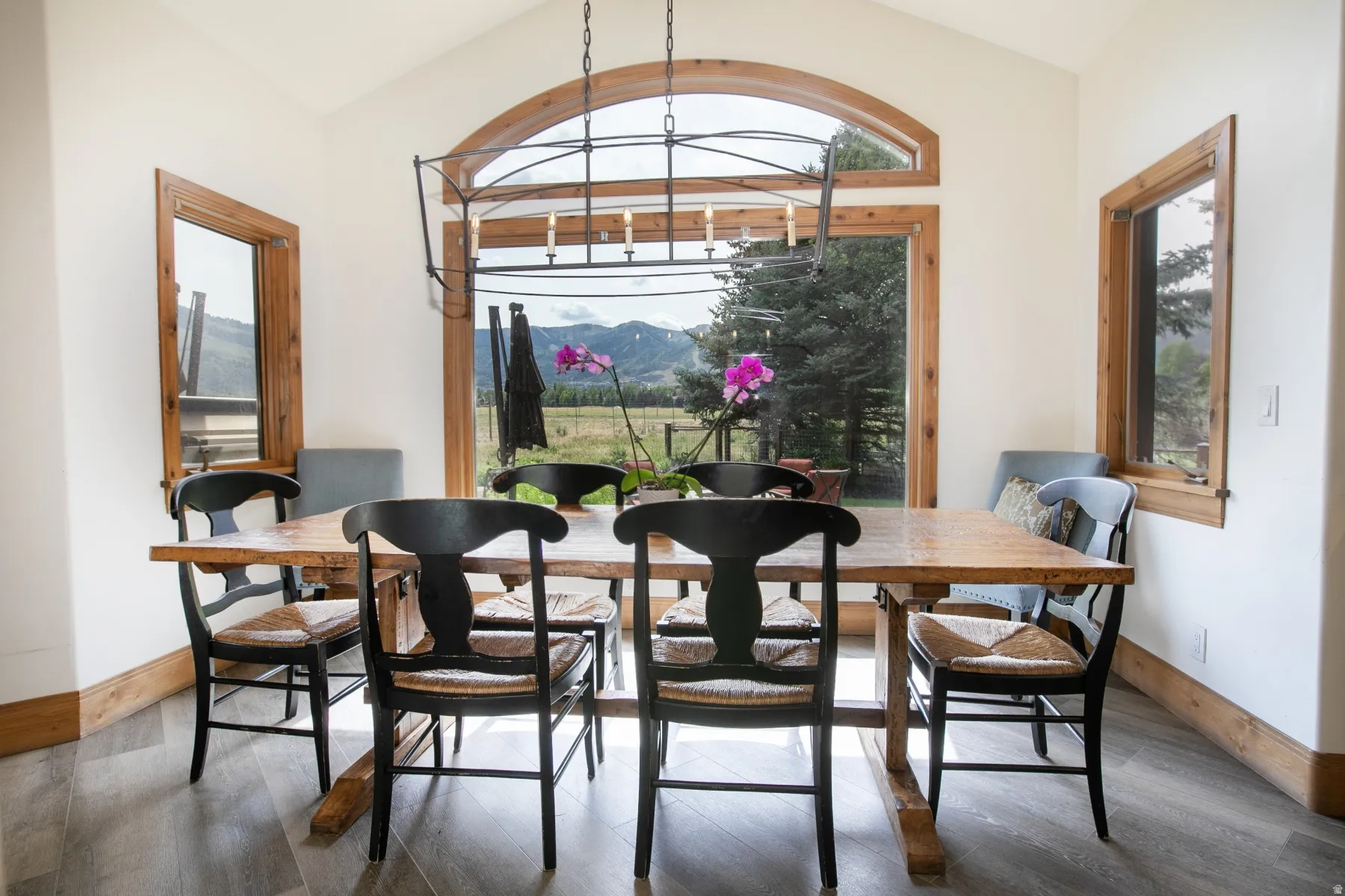 Arched window framing mountain and field scenery, complemented by two rectangular windows with wood trim
