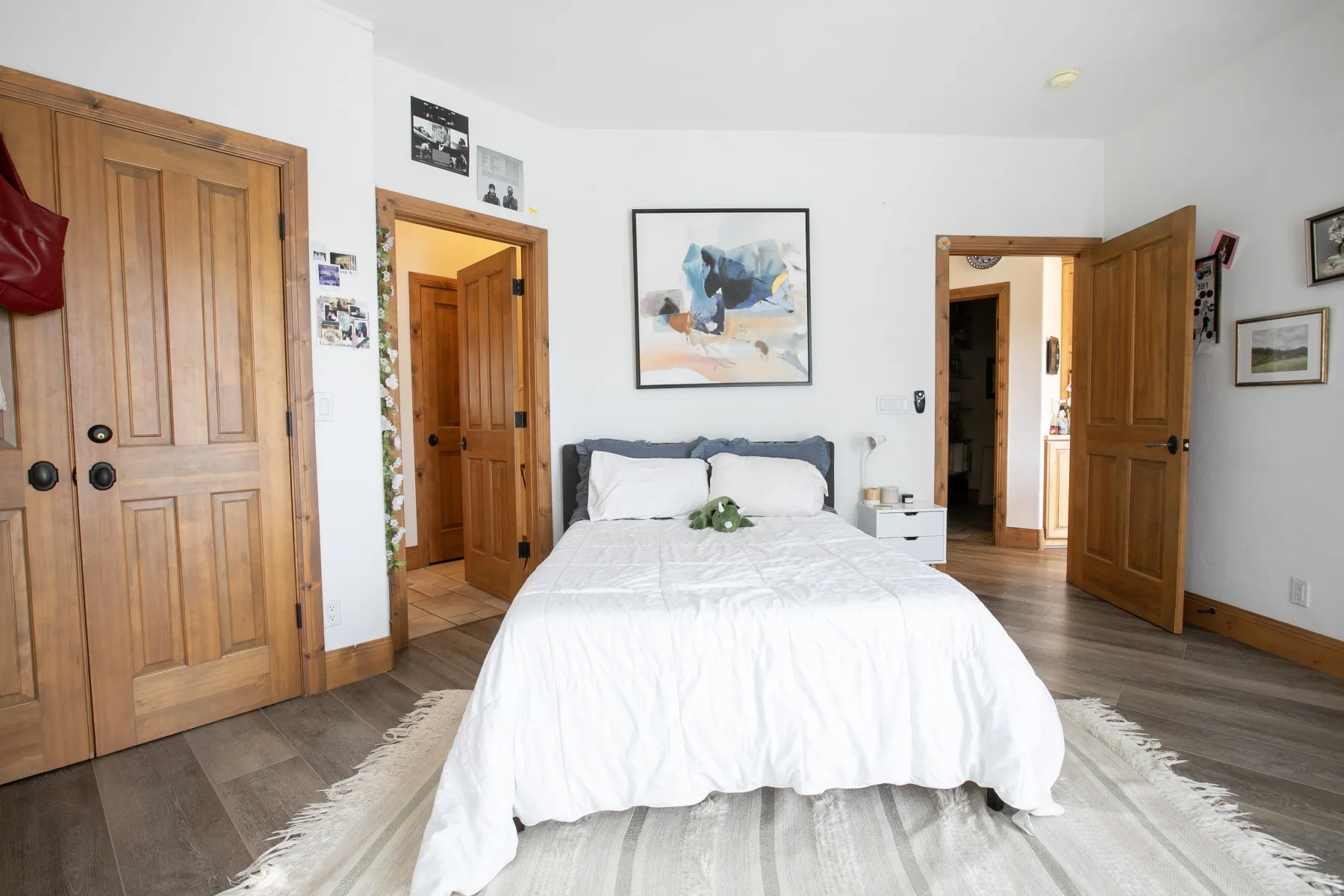 Spacious room featuring light wood-finish flooring, white walls, and natural wood doors