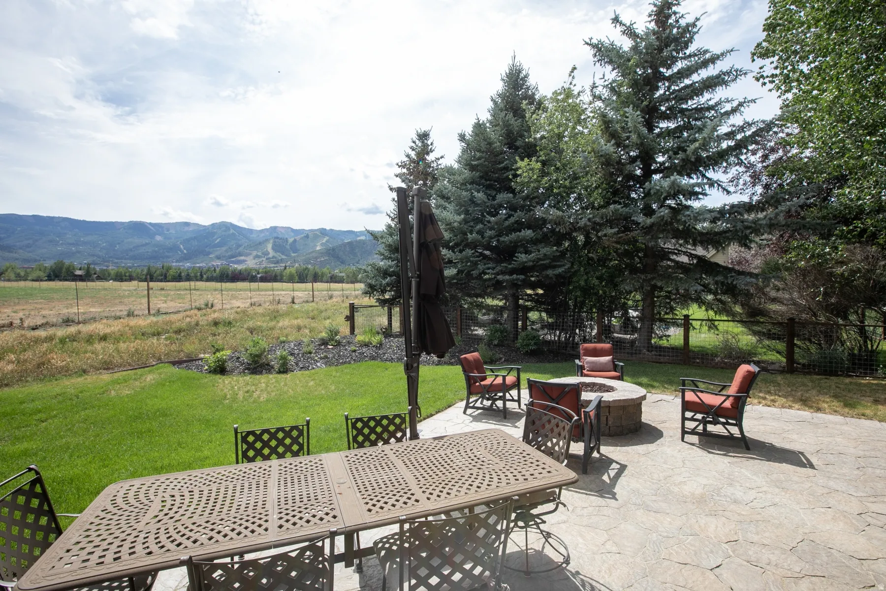 Expansive patio featuring a built-in fire pit and a stone-look surface