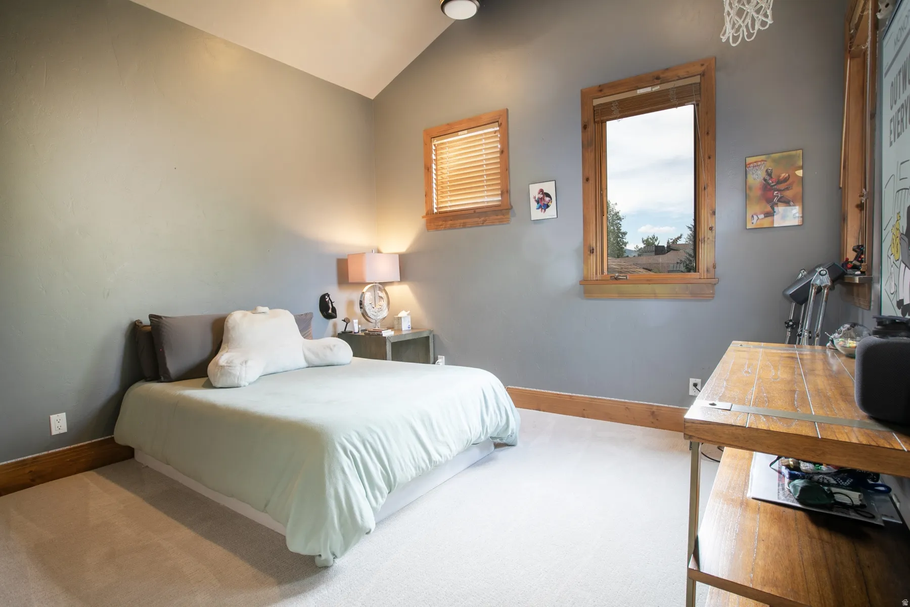 Carpeted room featuring a vaulted ceiling and two windows with wood trim