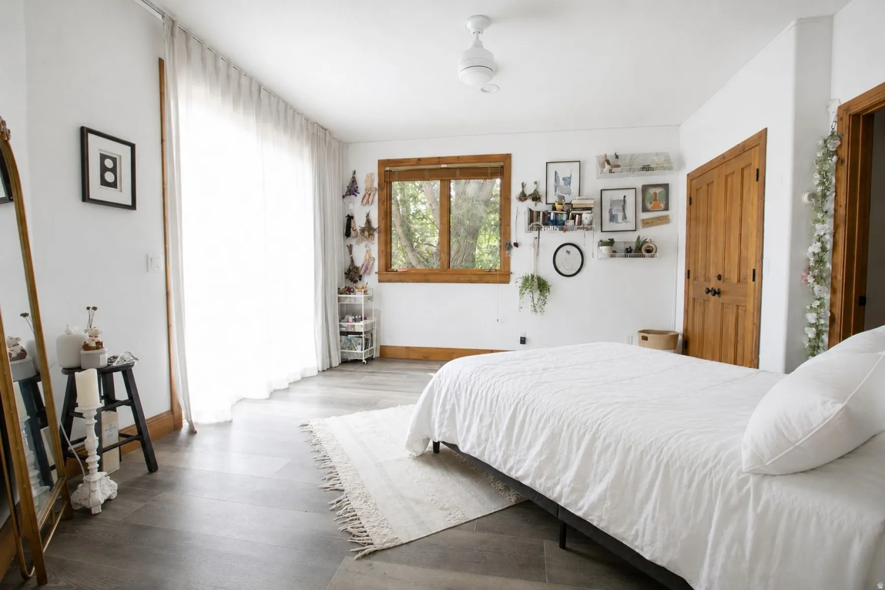 Spacious interior featuring wood-finish flooring, a ceiling fan, and a large window with wood trim