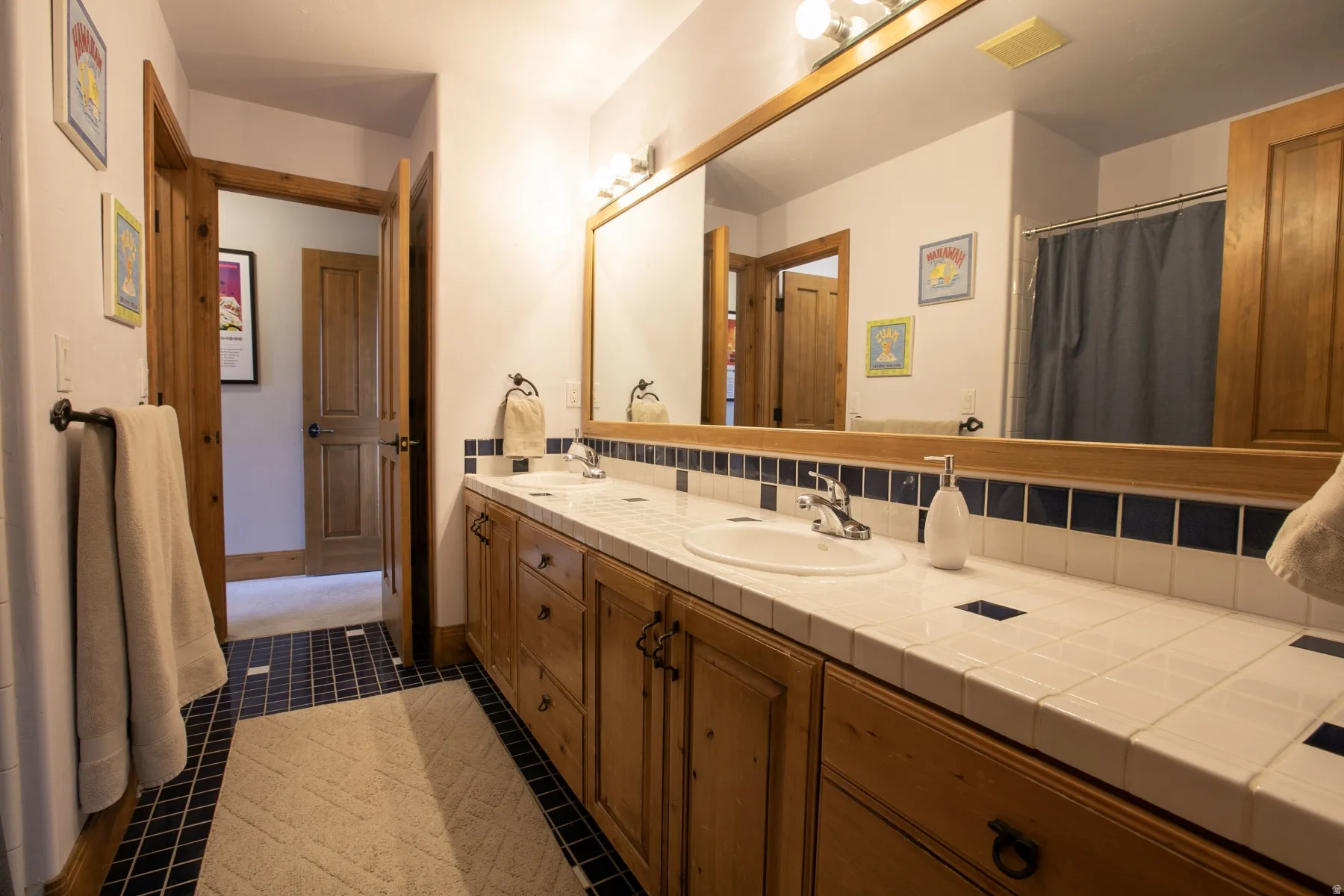 Double vanity with wood-finish cabinetry, white tiled countertop, and dual sinks