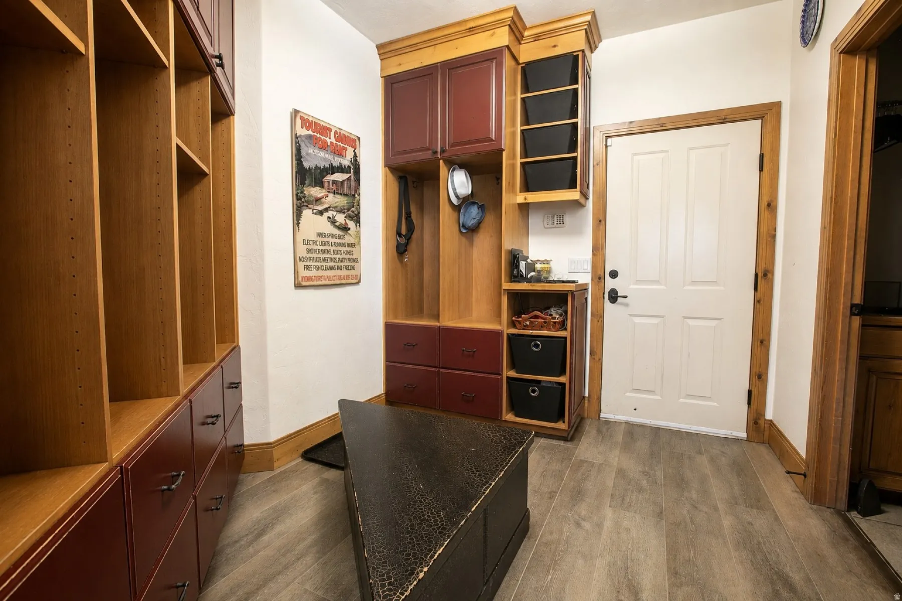 Entryway featuring built-in cabinetry with red and wood-finish accents, paneled door with wood trim, and wood-finish plank flooring